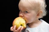 Baby-Entwicklung: Baby beißt in einen Apfel