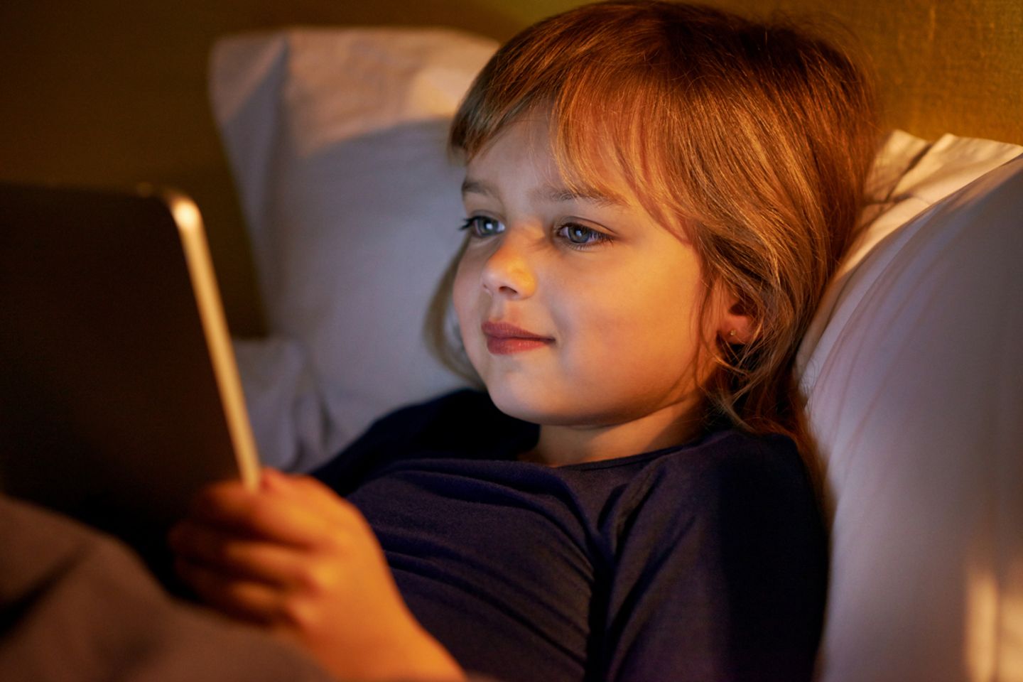 Kind im Bett mit Tablet