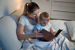 Mutter liest ihrem Kind im Bett ein Buch vor