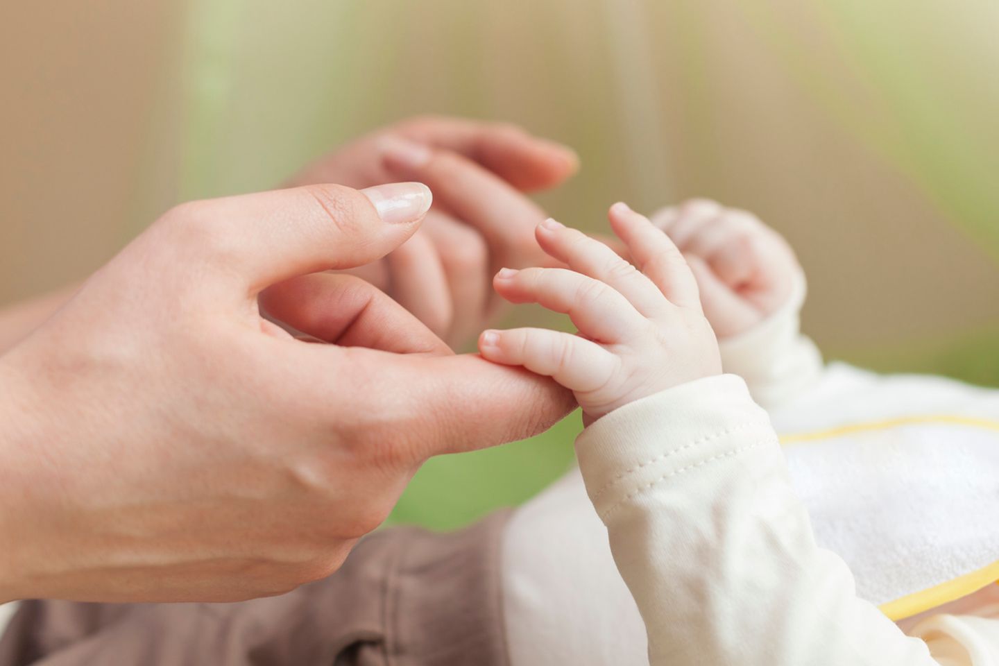 Mutter greift nach den Händen ihres Babys