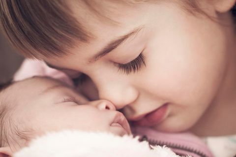 Baby im Arm von Kleinkind