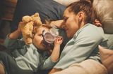 Mutter kuschelt mit Kind im Bett