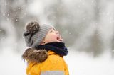 Ein Junge in warmen Winterklamotten im Schnee