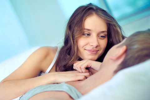 Zervixschleim: Junge Frau lächelt ihren neben ihr liegenden Partner an