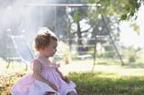 Kleines Mädchen sitzt alleine auf Spielplatz
