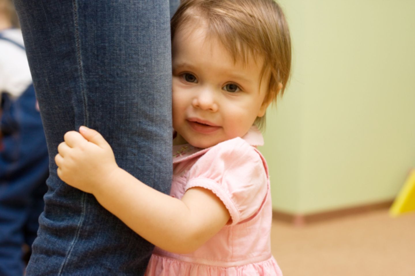 Kleinkind sucht Schutz am Bein der Mutter