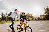 Kleiner Junge lernt mit seinem Papa Fahrrad fahren