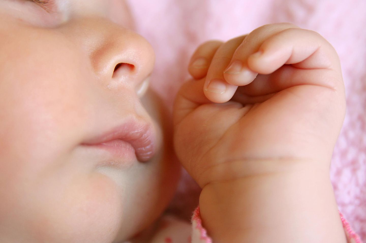 Nahaufnahme von Baby-Gesicht, bzw. von Nase und Hand