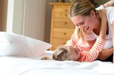 Mutter und Tochtern toben im Bett