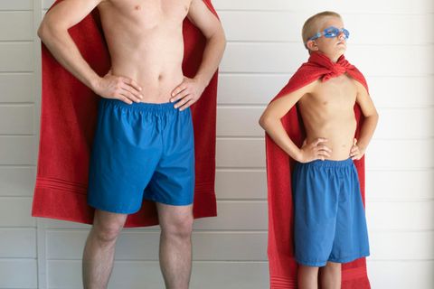 Vater und Sohn als Superman verkleidet, stehen identisch da