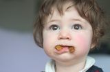 Kleinkind mit Mund voller Keks