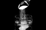 Salz rieselt in ein Glas