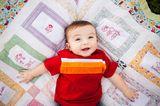 Beschäftigungsideen für dein Baby: Ein Baby liegt rücklings auf einer bunten Decke