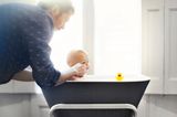 Beschäftigungsideen für dein Baby: Ein Mann badet ein Baby in einer kleinen Badewanne