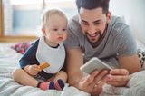 Beschäftigungsideen für dein Baby: Ein Baby schaut auf das Handy eines Mannes