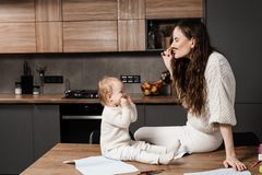 Beschäftigungsideen für dein Baby: Frau schneidet Grimassen vor Baby in der Küche
