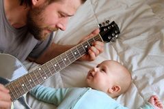 Beschäftigungsideen für dein Baby: Mann spielt Baby etwas auf der Gitarre vor