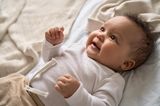 Beschäftigungsideen für dein Baby: Lachendes Baby liegt auf dem Rücken