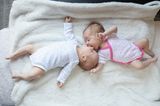 Zwei Babys liegen auf einer Decke
