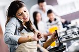 Fastenzeit: Frau mit Telefon am Ohr schaut auf die Uhr während sie kocht
