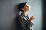 Fastenzeit: Frau lehnt an einer Wand und raucht eine Zigarette