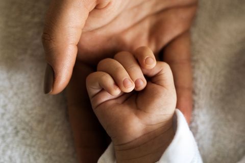 Mutter hält die Hand ihres Kindes.