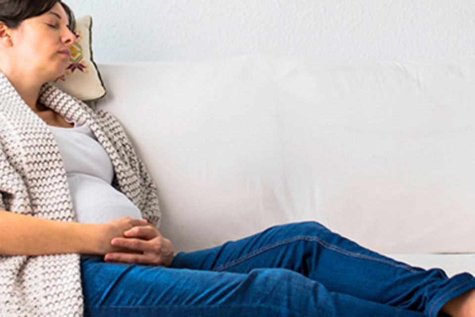 Schwangere Frau ruht sich auf Sofa aus