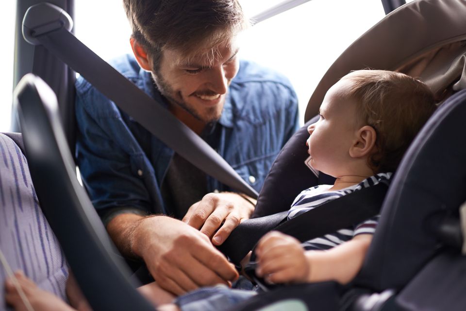 Vater schnallt Baby im Autositz an