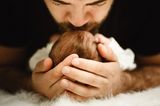 Vater küsst Baby auf Schaffell