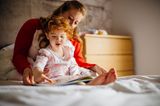 Leichter einschlafen: Eine Mutter und ihr Kind blättern in einem Bilderbuch.