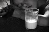 Leichter einschlafen: Ein Glas Milch steht bei einem schlafenden Jungen auf dem Nachttisch, Bild in schwarz-weiß.