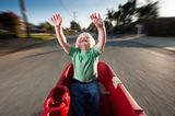 10 Geheimtipps für einen entspannten Urlaub: Kind im Bollerwagen reißt die Arme hoch