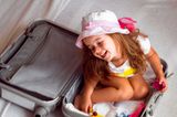 10 Geheimtipps für einen entspannten Urlaub: Kind sitzt in einem Koffer