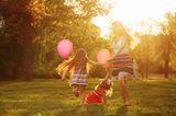 10 Geheimtipps für einen entspannten Urlaub: Frau und Kinder spielen mit Luftballons