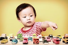 Welcher Spiel-Typ ist dein Kind? Kleines Kind zeigt mit dem Finger auf Spielzeugautos