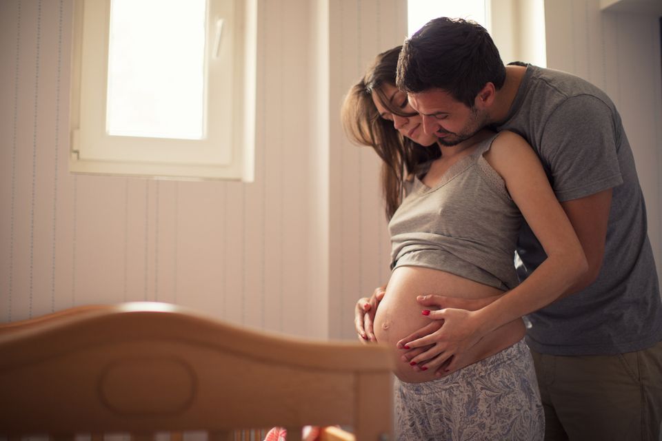 Senkwehen: Mann umfasst zärtlich den Babybauch der Frau