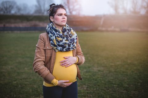 Wunschkaiserschnitt: Schwangere schaut nachdenklich und hält sich den Babybauch