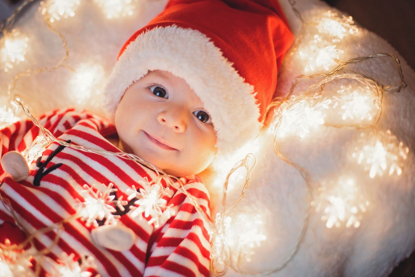 Baby mit Lichterkette zu Weihnachten