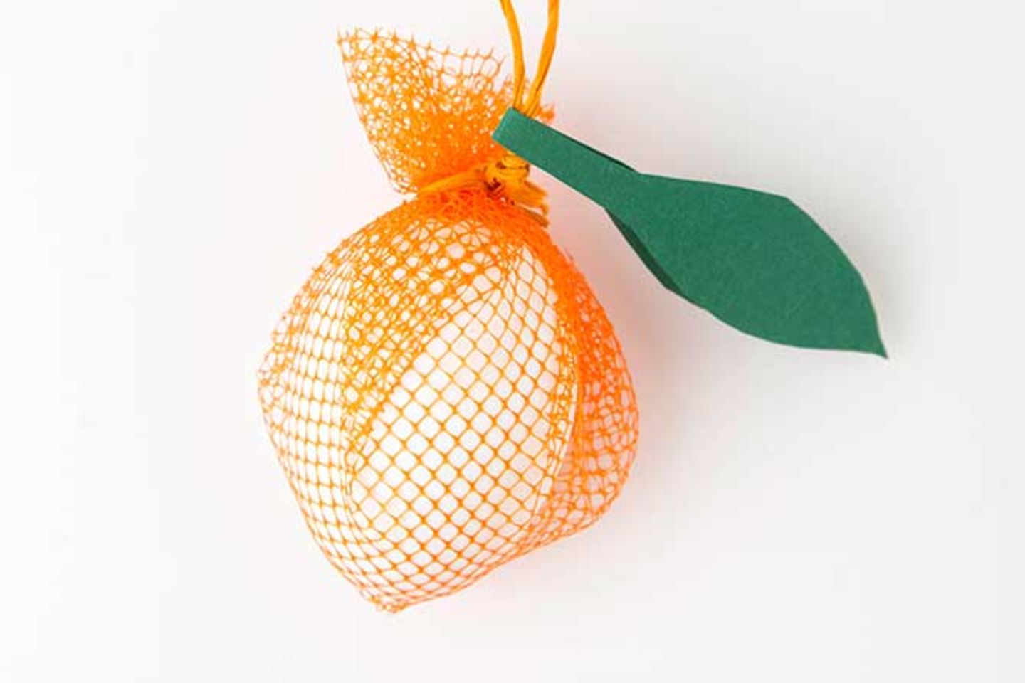 Für die Orange zwei über einen Steg verbundene Blätter ausschneiden, in der Mitte knicken und einfach über der Aufhängung baumeln lassen.