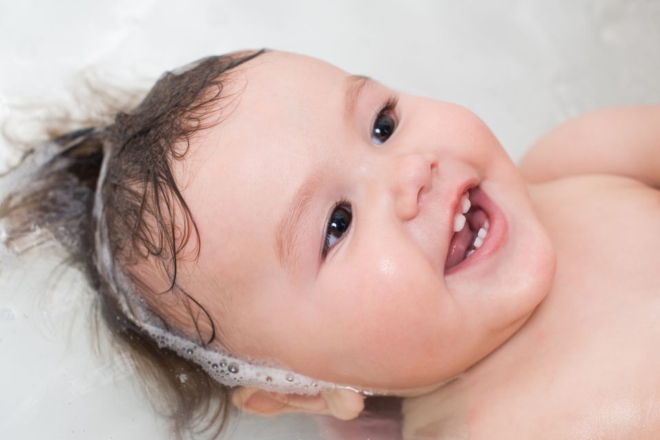Kleinkind badet lächelnd in der Badewanne