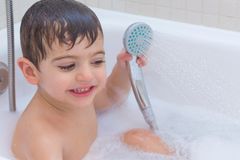 Junge spielt in der Badewanne mit der Handbrause