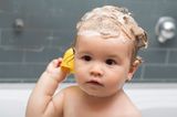Baby mit Shampoo im Haar in der Badewanne