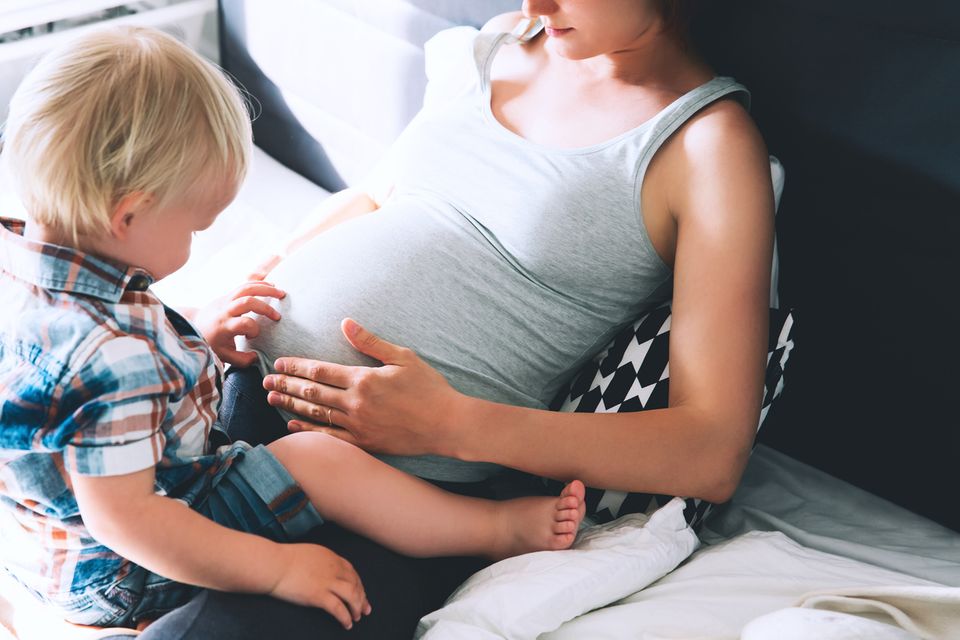 Schwangere mit Kind auf dem Schoß