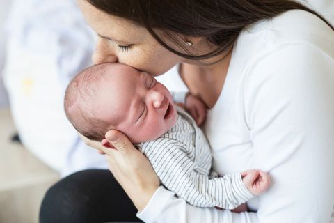 Dammschnitt bei der Geburt: Frau küsst ein Neugeborenes