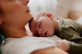 Neugeborenes schläft auf Brust der Mutter