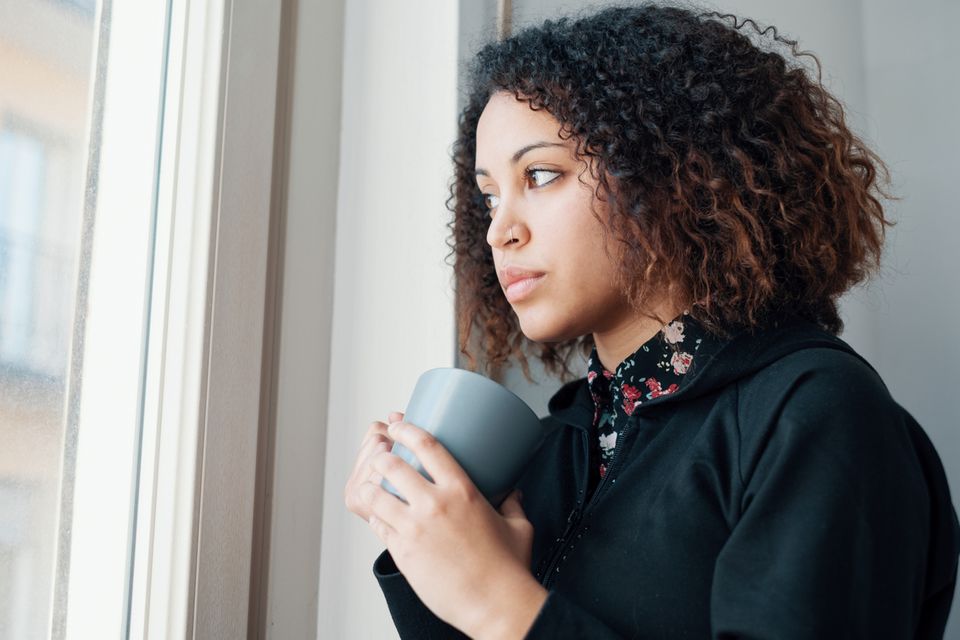 Missed Abortion: Junge Frau mit Becher in der Hand schaut aus dem Fenster