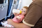 Baby mit Fläschchen im Flugzeug