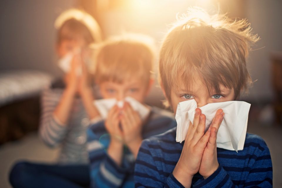 Drei Kinder putzen sich die Nase