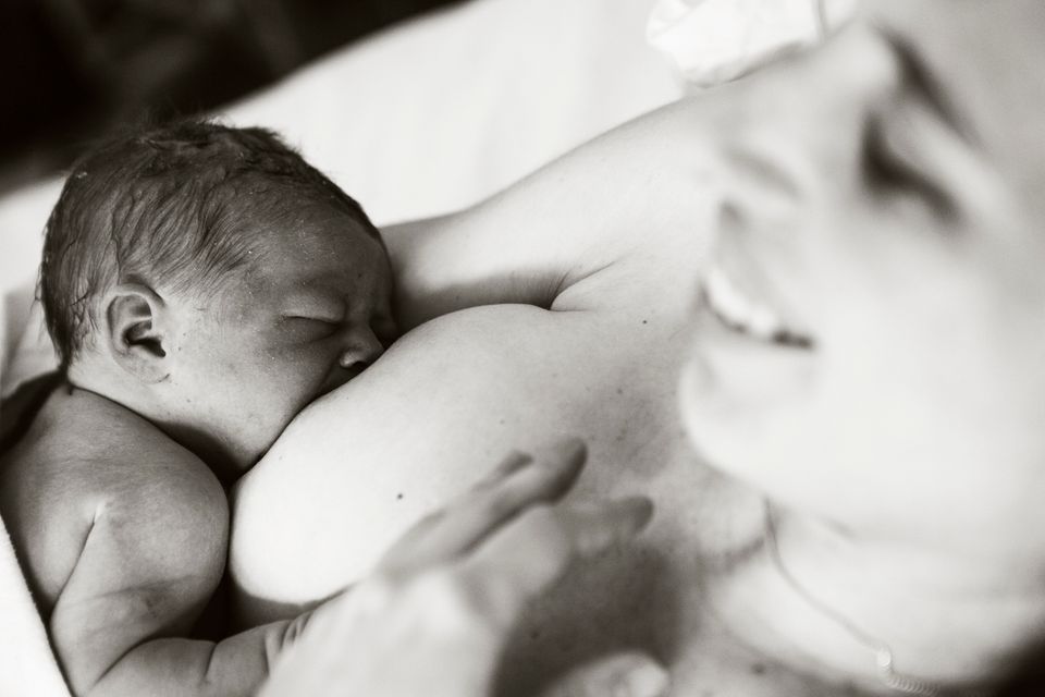 Glückliche Mutter stillt ihr Neugeborenes.