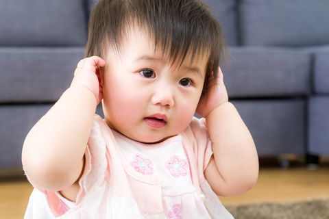 Kleines asiatisches Mädchen hält sich die Ohren